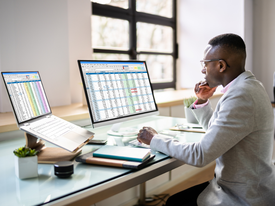 An accounting researcher sitting at a desk with two computer screens.