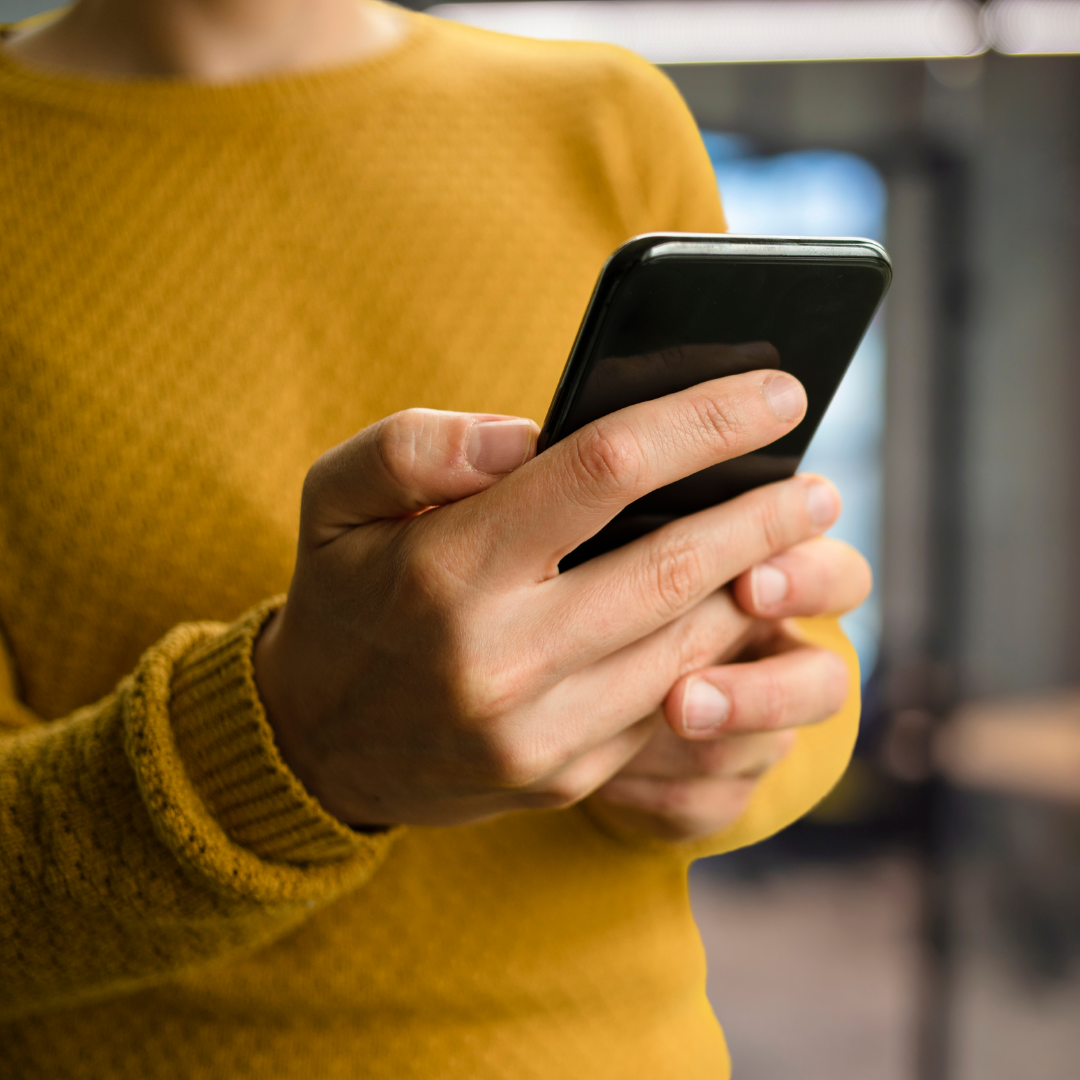 A person holding a cell phone in their hand. Looking to contact the DeGroote School of Business Research and Faculty team.