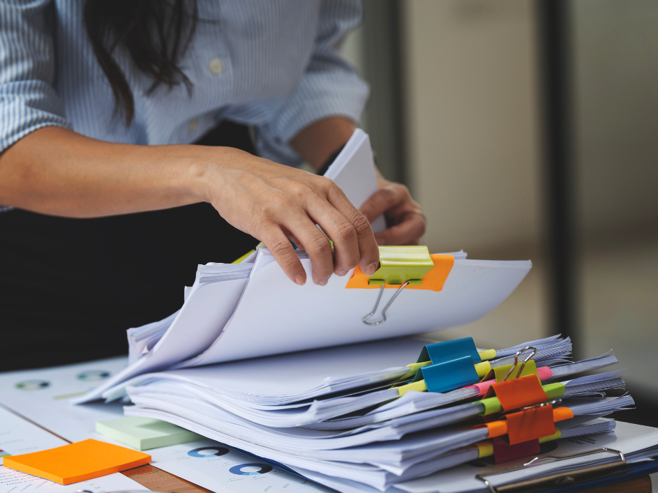 Woman holding stack of papers with clip, publications and studies.