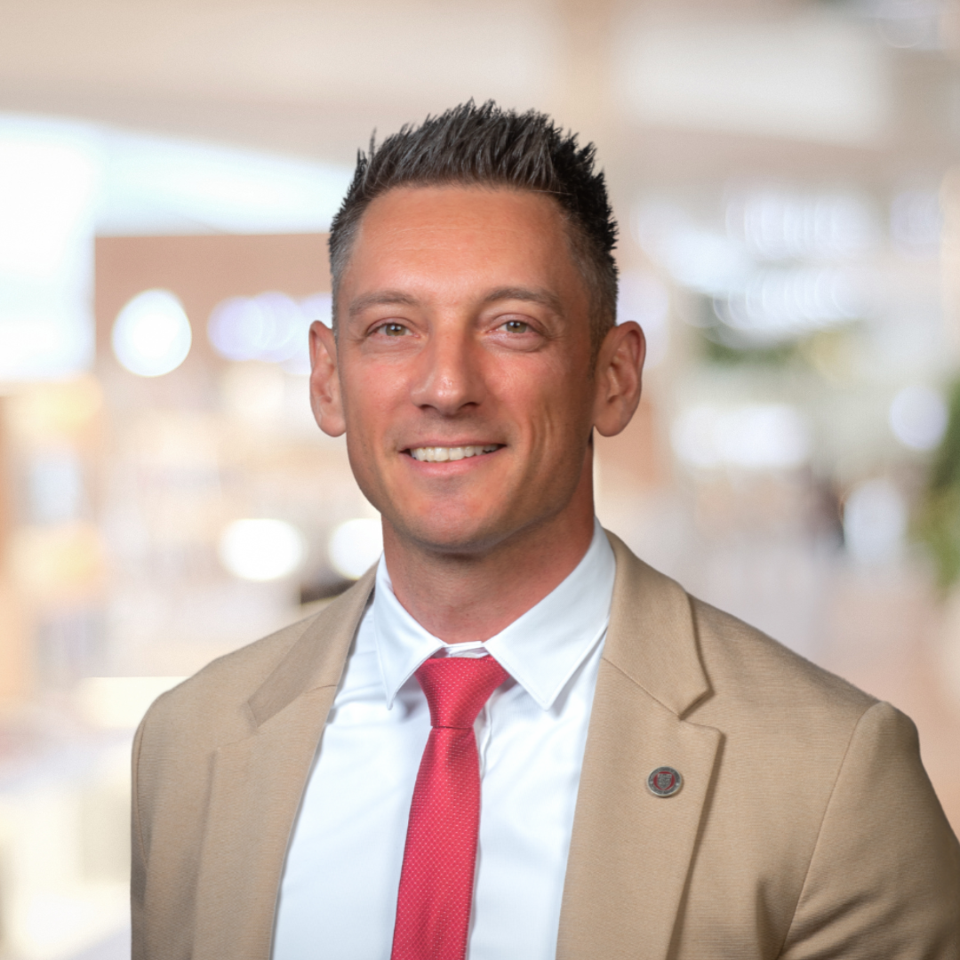 Headshot of Goran Calic, a smiling man wearing a cream suit with a red tie.