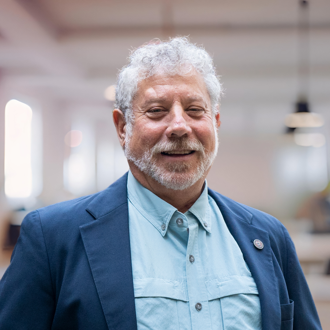 Headshot of Benson Honig, a smiling man with grey hair and a beard, wearing a blue blazer.