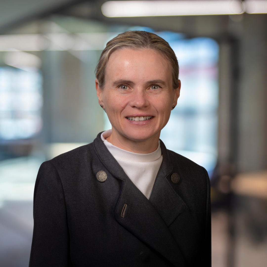 Headshot of Katya Malinova, a smiling woman wearing a dark grey jacket.