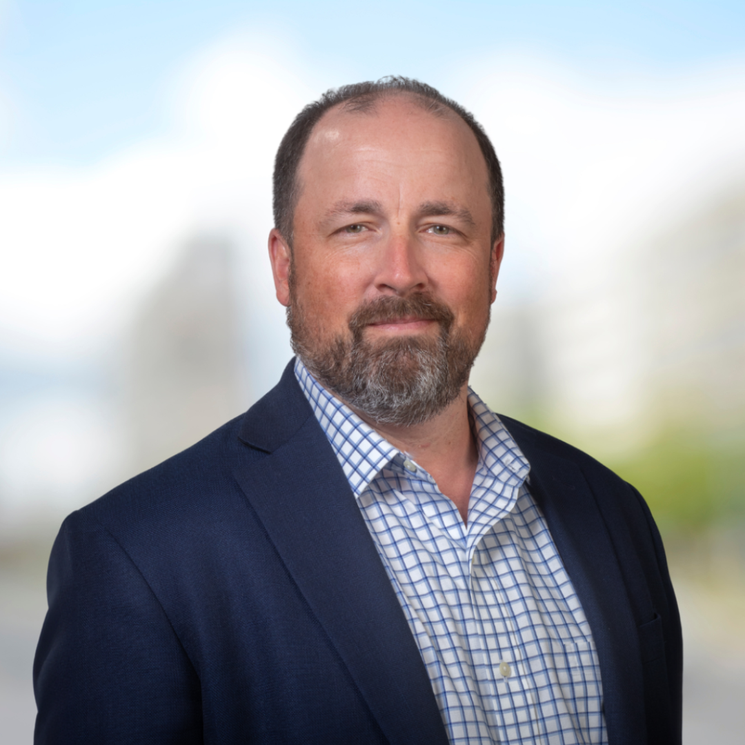 Headshot of Brent McKnight, a bearded smiling man wearing a navy blazer.